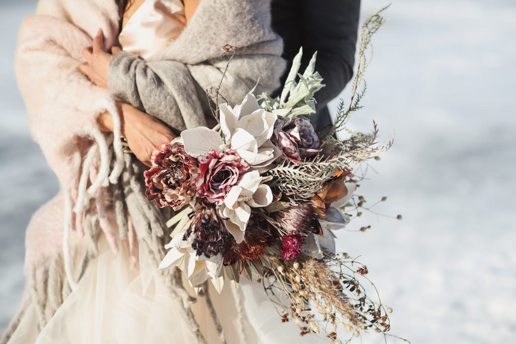 Ice wedding, ice dinner, tule bridal skirt, blush, burgundy, brown, dried florals, winter, frozen lake, styled shoot, bride and groom, bridal bouquet.