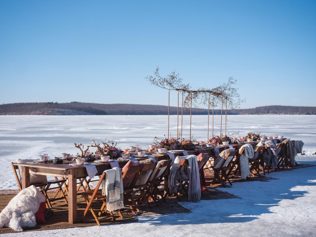 Ice wedding, ice dinner, tule bridal skirt, blush, burgundy, brown, dried florals, winter, frozen lake, styled shoot, dinner, table setting, blankets, ribbons, dried centerpiece.